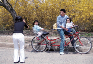 A family taking pictures with their family members on a tandem bicycle