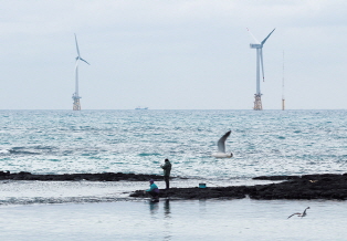 Secluded beach scenery with Mulphy wind turbines visible